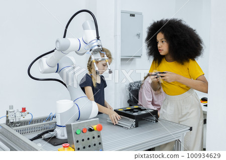 Girl with afro hairstyle wear yellow T-shirt using joystick control smart robotics arm. 100934629