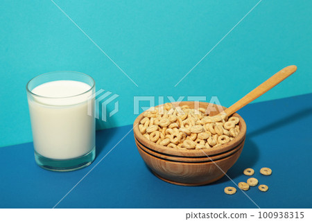 Bowl with cereals and a glass bottle of milk on blue background. Top view Bowl with cereals and a glass bottle of milk on blue background. Top view 100938315