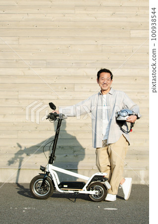 Senior man riding an electric kickboard Senior man riding an electric kickboard 100938544