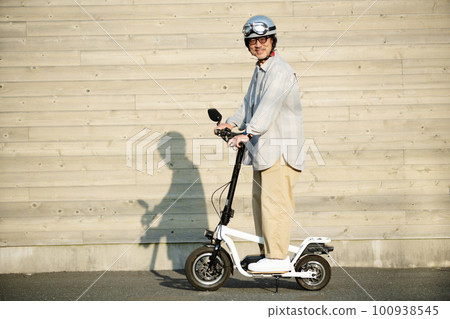 Senior man riding an electric kickboard Senior man riding an electric kickboard 100938545