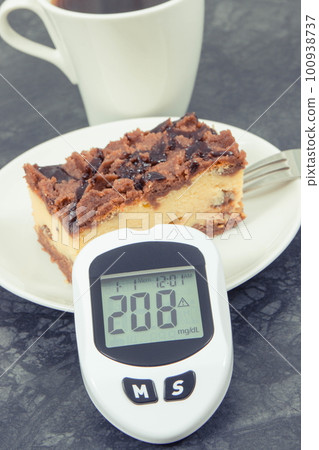 Glucose meter with high and bad result sugar level and fresh baked cheesecake with coffee Glucose meter with high and bad result sugar level and fresh baked cheesecake with coffee 100938737