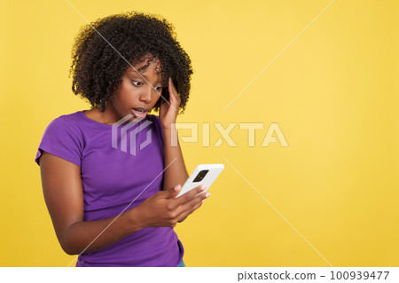 Worried woman with afro hair using a mobile phone Worried woman with afro hair using a mobile phone 100939477