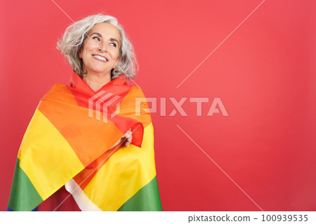 Smiley mature woman wrapped with a lgbt flag 100939535