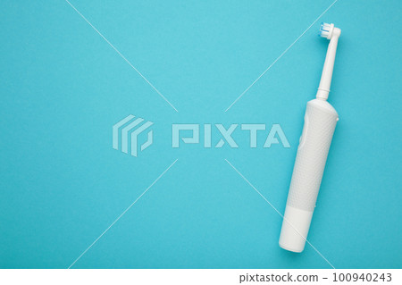 Modern electric toothbrush on blue background. Controlled tool for daily oral care. Space for text 100940243