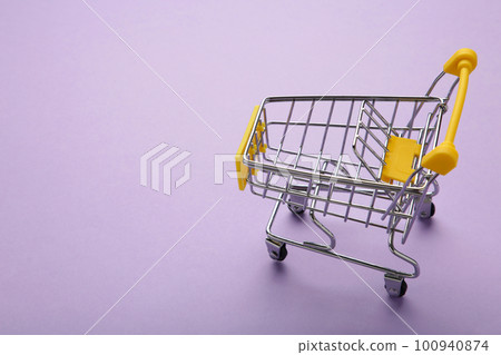 Mini shopping trolley on purple background. Space for text Mini shopping trolley on purple background. Space for text 100940874