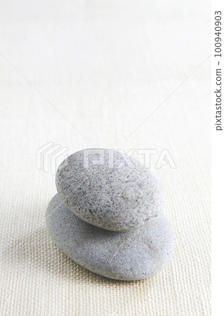 Round stones with sharpened corners are piled up on a white cotton fabric and photographed using the blank space Round stones with sharpened corners are piled up on a white cotton fabric and photographed using the blank space 100940903