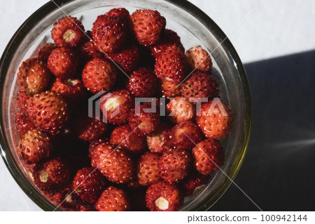 Wild strawberries in the glass on the old windowsill lit by the sun. Close up Wild strawberries in the glass on the old windowsill lit by the sun. Close up 100942144