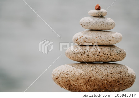 Pyramid stones on seashore with warm sunset on sea background for perfect holiday. Pebble beach and calm sea create a serene travel destination. concepts of happy vacation, meditation spa and calmness Pyramid stones on seashore with warm sunset on sea background for perfect holiday. Pebble beach and calm sea create a serene travel destination. concepts of happy vacation, meditation spa and calmness 100943317