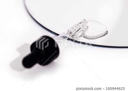 Close up of gel or serum glass pipette with transparent drops on white background. 100944625