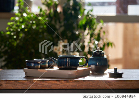 Tea set of deep blue color on a background of greenery. Tea set of deep blue color on a background of greenery. 100944984