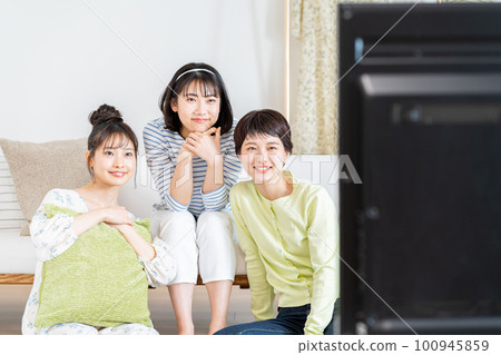 在客廳和朋友一起看電視的年輕女人 100945859
