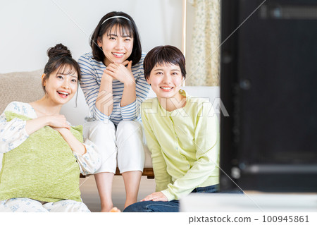 在客廳和朋友一起看電視的年輕女人 在客廳和朋友一起看電視的年輕女人 100945861