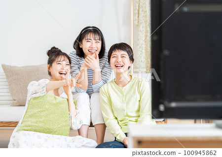 在客廳和朋友一起看電視的年輕女人 在客廳和朋友一起看電視的年輕女人 100945862