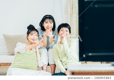 在客廳和朋友一起看電視的年輕女人 在客廳和朋友一起看電視的年輕女人 100945863