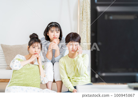 在客廳和朋友一起看電視的年輕女人 在客廳和朋友一起看電視的年輕女人 100945867