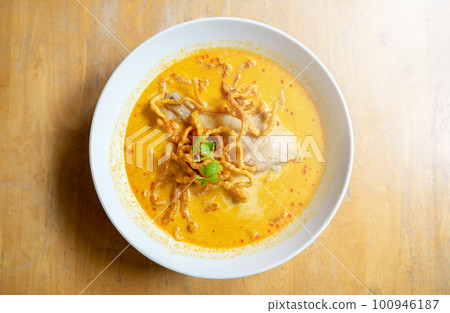 Thai Food, Khao Soi Kai, Thai spicy food, Thai spicy soup, Egg noodle in chicken curry on old wooden table background. Thai Food, Khao Soi Kai, Thai spicy food, Thai spicy soup, Egg noodle in chicken curry on old wooden table background. 100946187