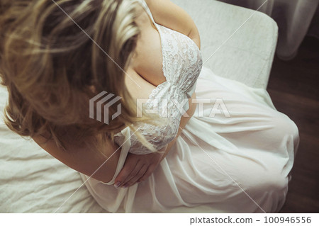 Luxury woman with big breasts hugs herself on the bed 100946556