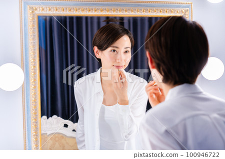 Middle-aged woman applying lipstick Middle-aged woman applying lipstick 100946722