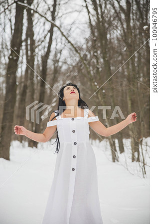 Attractive woman in white dress praying in the winter forest Attractive woman in white dress praying in the winter forest 100946795