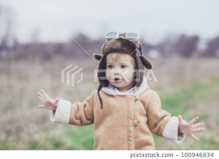 Charming baby in a pilot's clothes raised her hands as if flying Charming baby in a pilot's clothes raised her hands as if flying 100946834