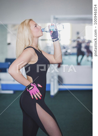 Beautiful blonde in leggings drinking water in the gym 100946854
