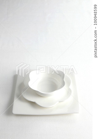 Petal-shaped white porcelain tableware and square plate Taken from an oblique bird's-eye view on a white background Petal-shaped white porcelain tableware and square plate Taken from an oblique bird's-eye view on a white background 100948599
