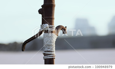 Rusty old metal water pump on sand beach 100948979