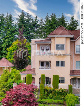 Italian style low-rise residential building with decorative trees in front 100949060