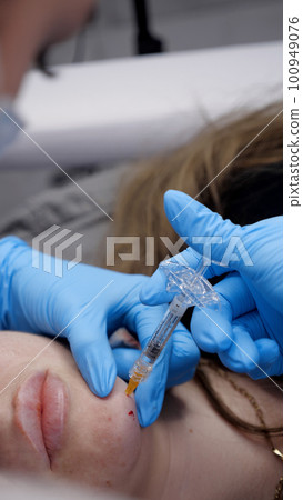 A doctor inserts painkillers into the chin area of womans face A doctor inserts painkillers into the chin area of womans face 100949076