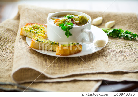 Hot cooked soup with Brussels sprouts, vegetables and croutons, in a plate. 100949359