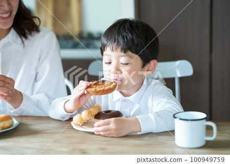 mother and son eating donuts mother and son eating donuts 100949759