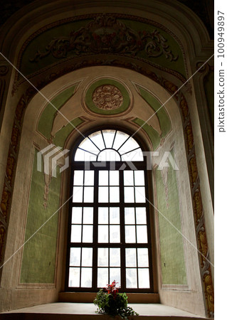 The interior is a vintage hall with a high ceiling and a huge window 100949897