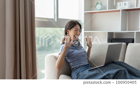 Young Asian woman greets his friends and teachers in a live video with a smile on his face, Online communication , Stay home, New normal, VDO Call, Social distancing, Internet learning. Young Asian woman greets his friends and teachers in a live video with a smile on his face, Online communication , Stay home, New normal, VDO Call, Social distancing, Internet learning. 100950405
