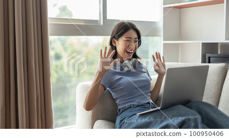 Young Asian woman greets his friends and teachers in a live video with a smile on his face, Online communication , Stay home, New normal, VDO Call, Social distancing, Internet learning. Young Asian woman greets his friends and teachers in a live video with a smile on his face, Online communication , Stay home, New normal, VDO Call, Social distancing, Internet learning. 100950406