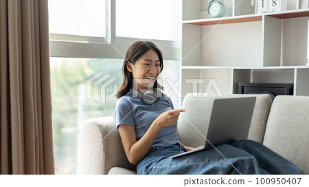 Young Asian woman greets his friends and teachers in a live video with a smile on his face, Online communication , Stay home, New normal, VDO Call, Social distancing, Internet learning. Young Asian woman greets his friends and teachers in a live video with a smile on his face, Online communication , Stay home, New normal, VDO Call, Social distancing, Internet learning. 100950407