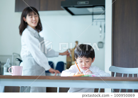 A child who draws and a mother who watches over while doing housework 100950869