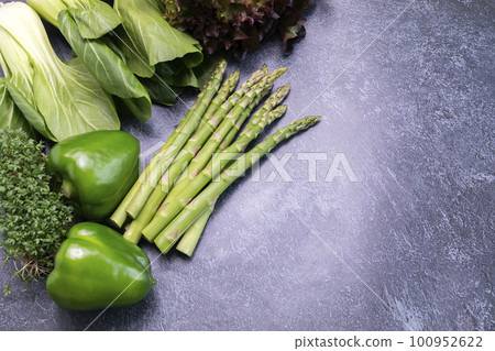 Flatly Assortment Of Fresh Organic Home Grown Green Vegetables On Gray Granite Table. Asparagus Plant, Bell Pepper, Bok Choy, Red Leaf Lettuce, Bittercresses. Healthy bio food.Horizontal, copy space. 100952622