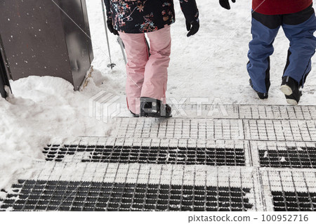 A skier descending the snow-covered grating stairs 100952716