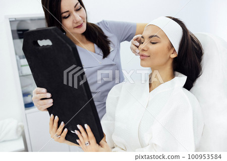 Doctor checking woman face skin in cosmetology clinic before plastic surgery Doctor checking woman face skin in cosmetology clinic before plastic surgery 100953584