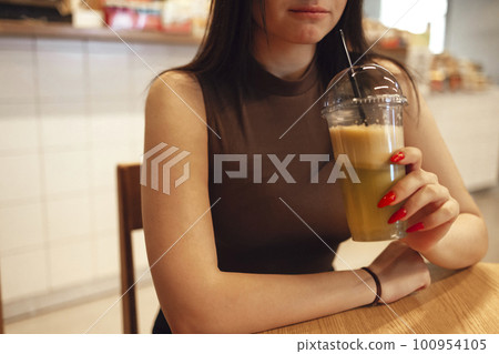 Happy young white girl drinking green smoothies in a stylish cafe indoor. Happy young white girl drinking green smoothies in a stylish cafe indoor. 100954105