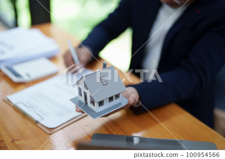 Guarantee, Mortgage, agreement, contract, Signing, Male client holding pen to reading agreement document to sign land loan with real estate agent or bank officer. Guarantee, Mortgage, agreement, contract, Signing, Male client holding pen to reading agreement document to sign land loan with real estate agent or bank officer. 100954566
