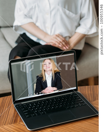 Online counseling. Web chat. Remote conference. Female professional expert on laptop screen working with woman on couch at home interior. Online counseling. Web chat. Remote conference. Female professional expert on laptop screen working with woman on couch at home interior. 100955346