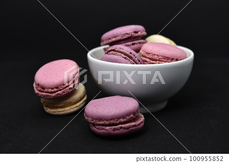 Macaroons in a white plate on a black background. Macaroons in a ceramic bowl. Colorful sweet cookies. 100955852