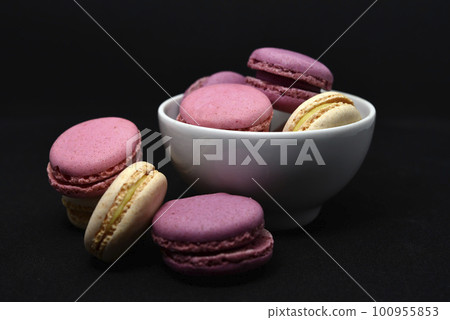 Macaroons in a white plate on a black background. Macaroons in a ceramic bowl. Colorful sweet cookies. Macaroons in a white plate on a black background. Macaroons in a ceramic bowl. Colorful sweet cookies. 100955853
