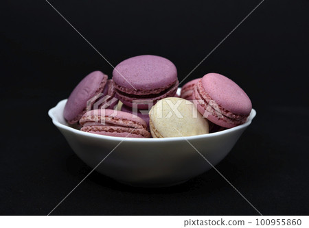 Macaroons in a white plate on a black background. Macaroons in a ceramic bowl. Colorful sweet cookies. Macaroons in a white plate on a black background. Macaroons in a ceramic bowl. Colorful sweet cookies. 100955860