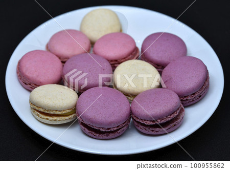 Macaroons in a white plate on a black background. Colorful sweet cookies. 100955862
