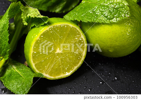 Fresh fruit close-up. Lime and mint leaves on a dark background 100956303