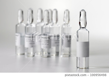 Medical ampoule with medicine, on a gray background. Vaccination and Immunization. Medical ampoule with medicine, on a gray background. Vaccination and Immunization. 100956498