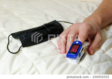 A pulse oximeter on a male finger used to measure the oxygen level in the blood. A pulse oximeter on a male finger used to measure the oxygen level in the blood. 100956505