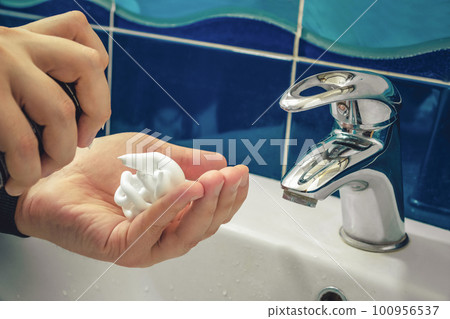 Hands of a man apply shaving foam in the bathroom close-up. Hygiene, skin care 100956537
